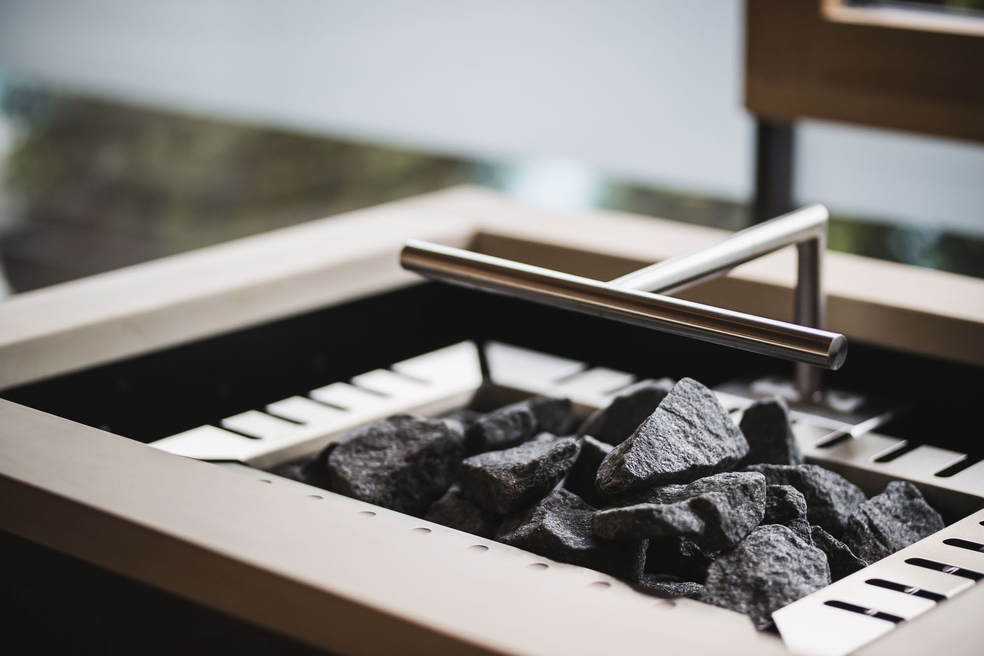 A close-up of a sink with a metal handle and a pile of black rocks inside.