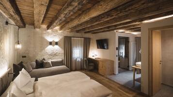 Una camera da letto con soffitto in legno, un letto, una scrivania e una televisione.