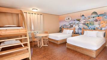 A room with two single beds, a bunk bed, a round table, and chairs.