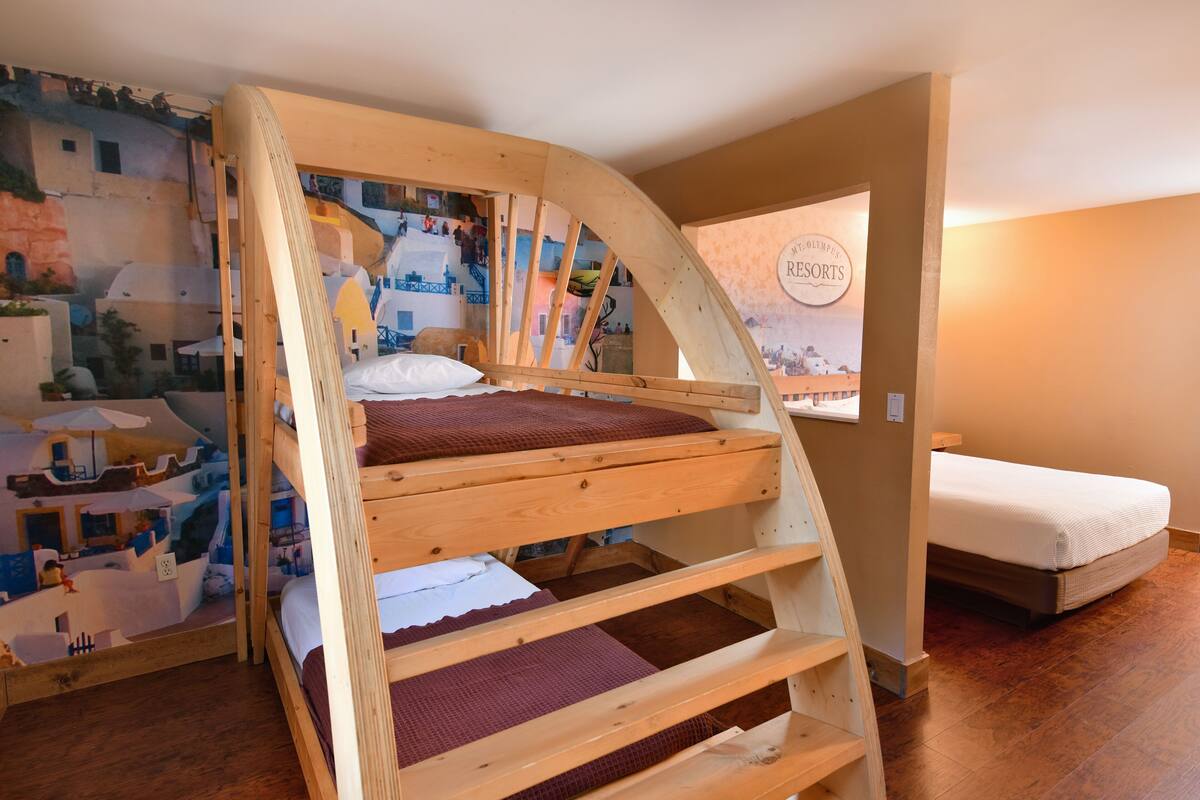 A bunk bed with a wooden frame and a mural of a coastal town on the wall behind it.