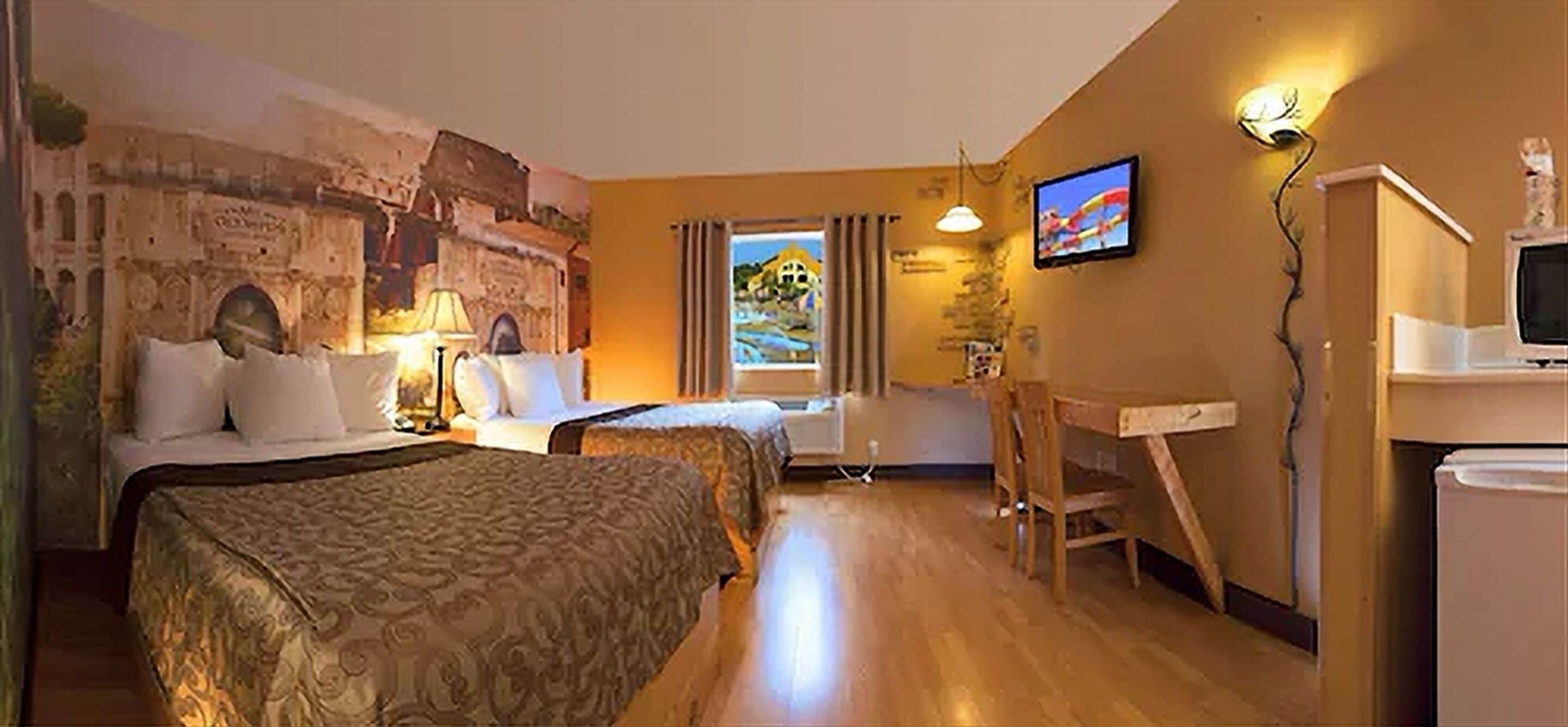 A hotel room with two beds, a desk, a television, and a mural on the wall.