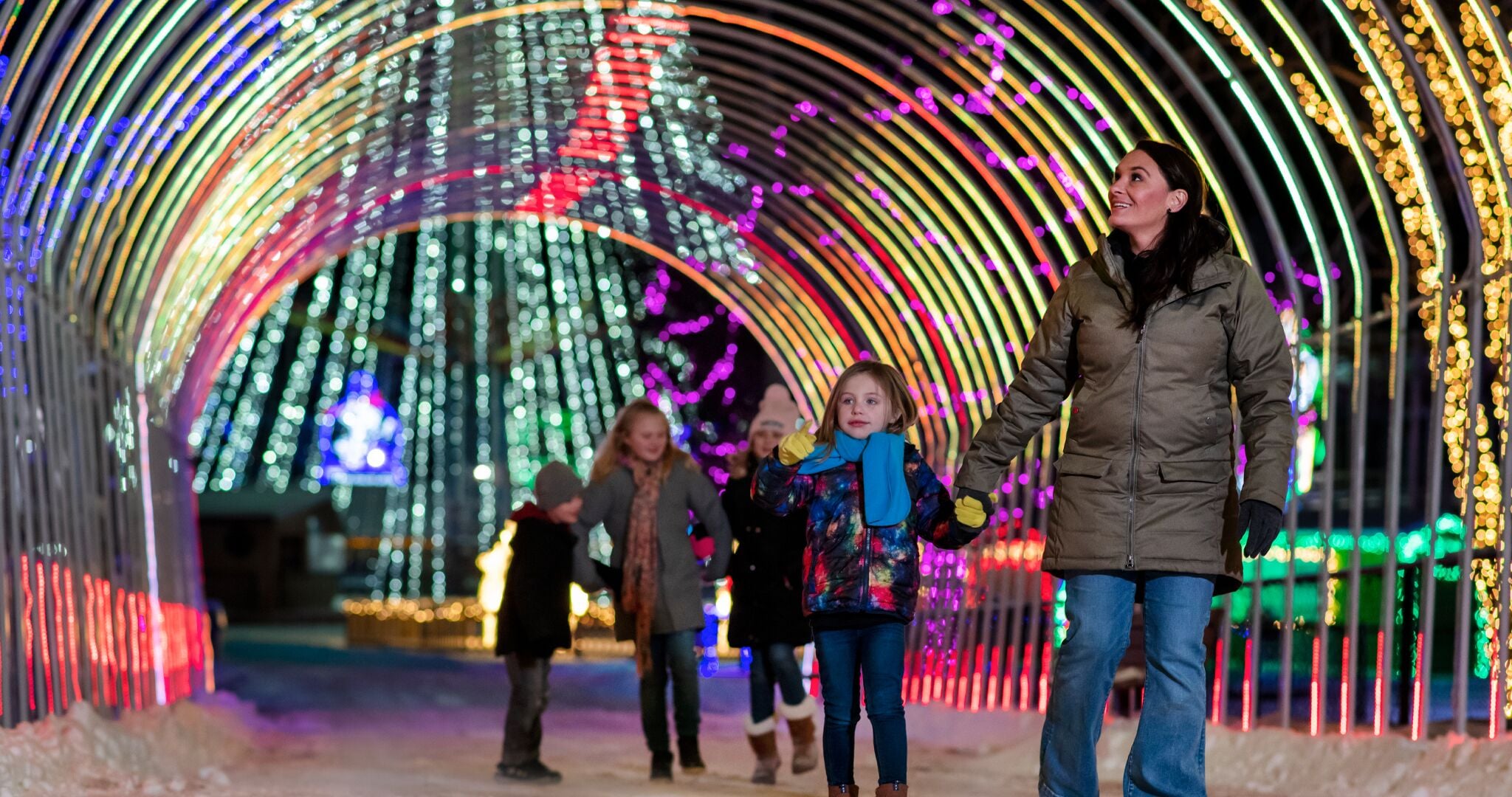 Un tunnel illuminé de lumières colorées et agrémenté de décorations.