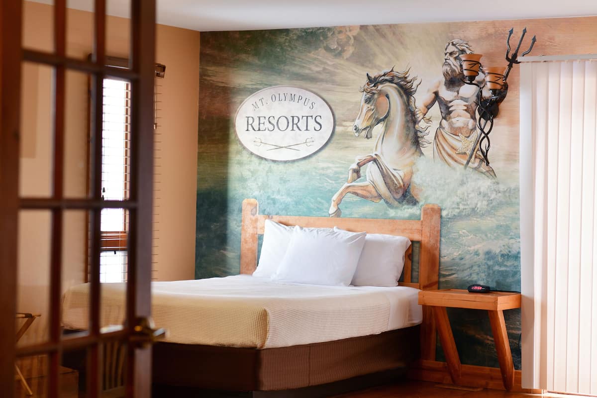 A bedroom with a bed, a wooden headboard, a nightstand, and a mural of a horse and rider.