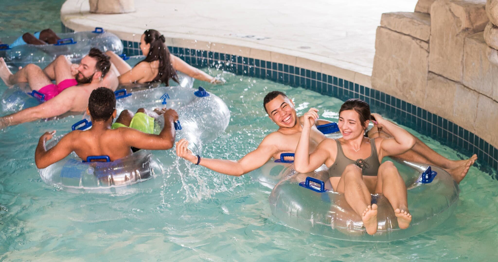 A swimming pool with people floating on inner tubes.