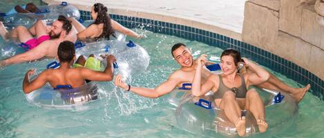A swimming pool with people floating on inner tubes.