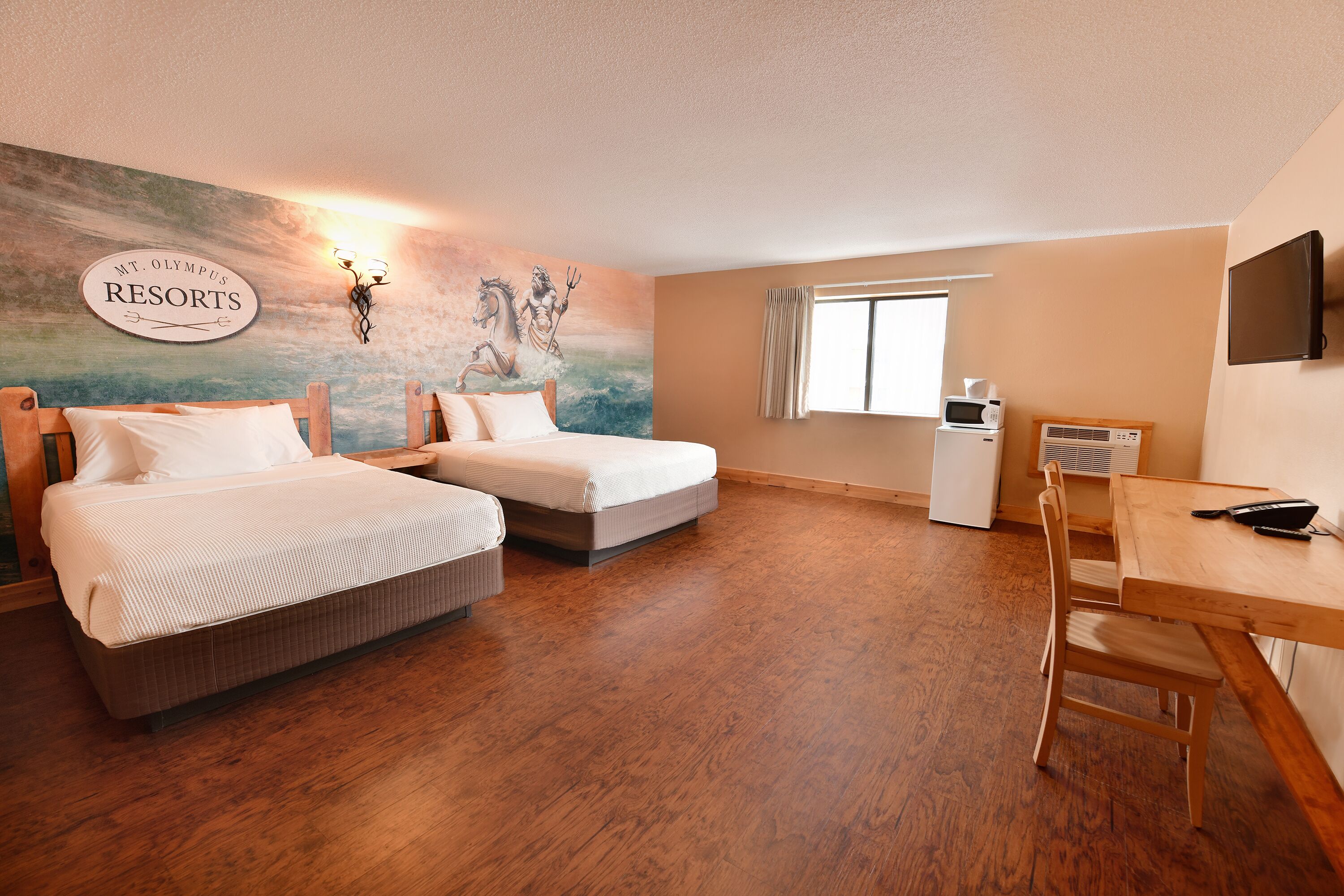 A hotel room with two beds, a desk, a TV, and a painting on the wall.