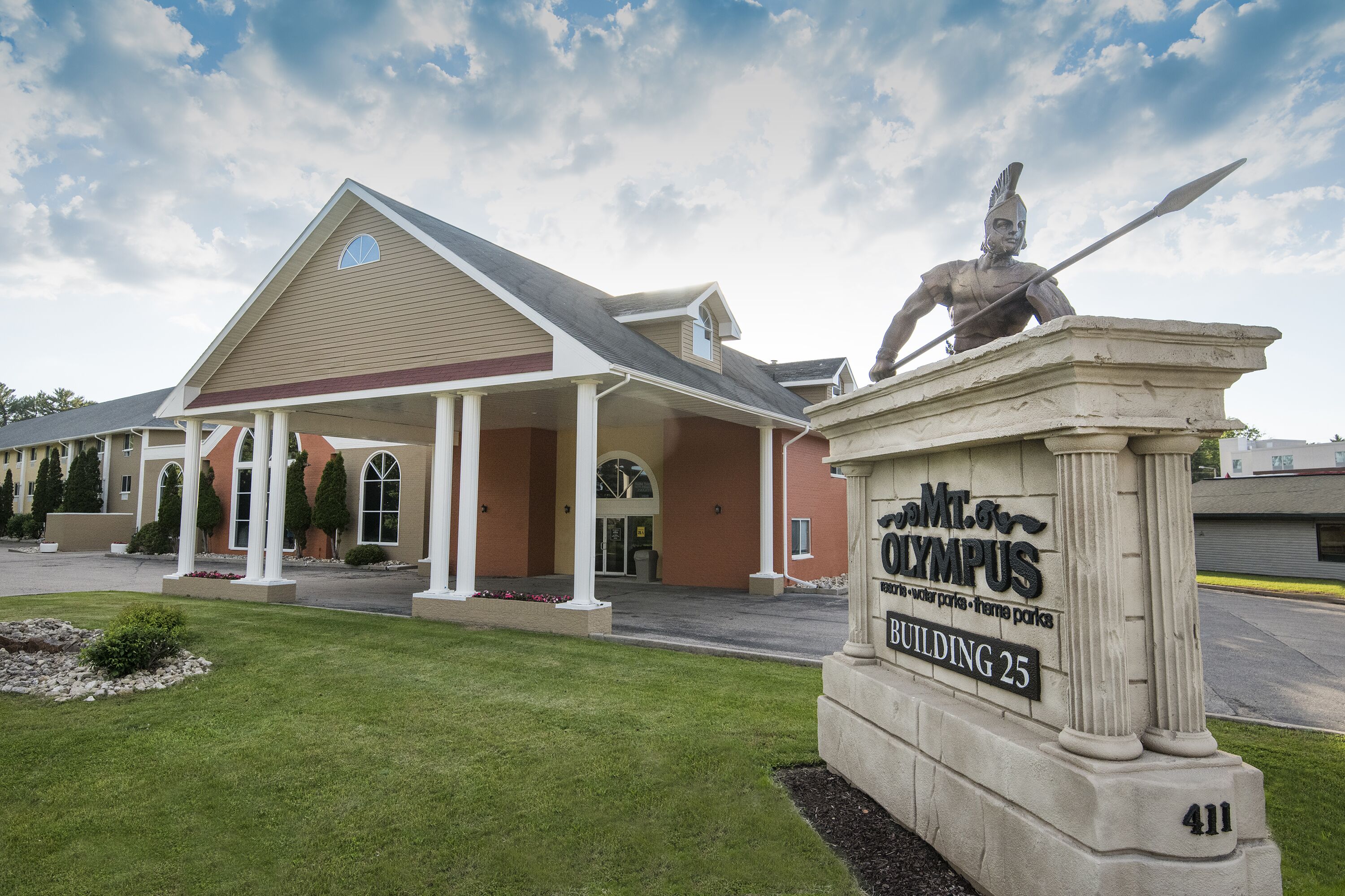 A building labeled "Mt. Olympus Building 25" with a statue of a warrior on a pedestal in front.
