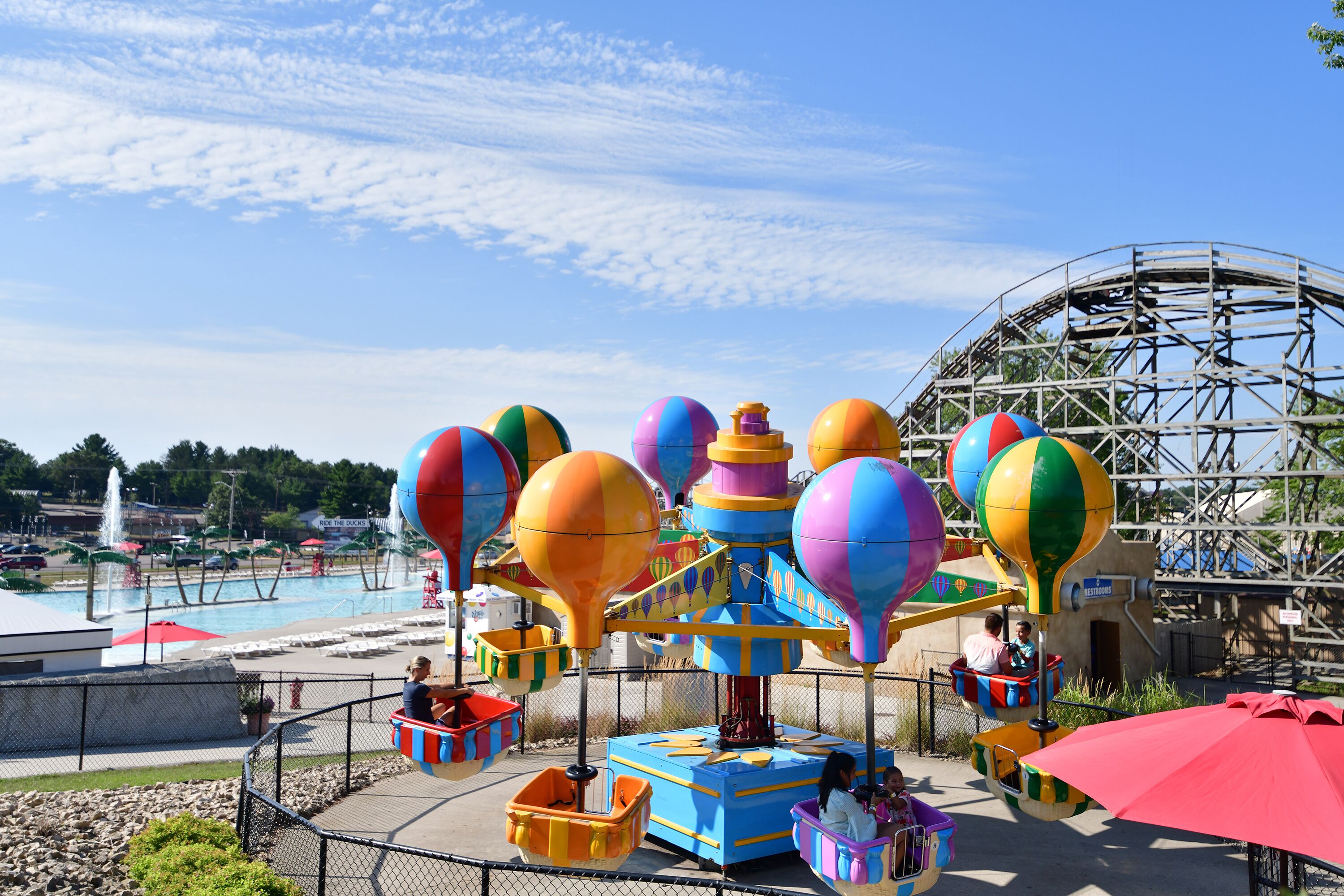 A colorful amusement park ride with a large water attraction in the background.