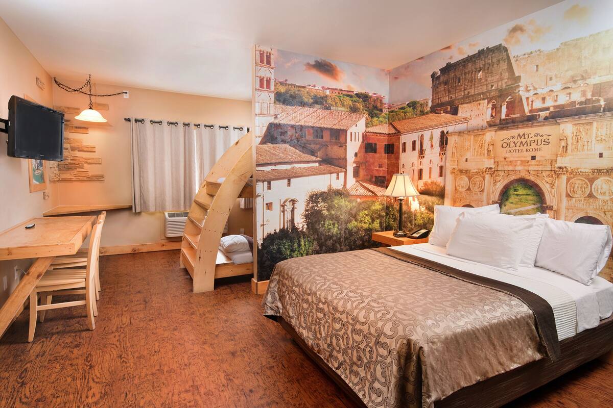 A bedroom with a bed, a desk, and a chair. There is a mural on the wall depicting a historical building.