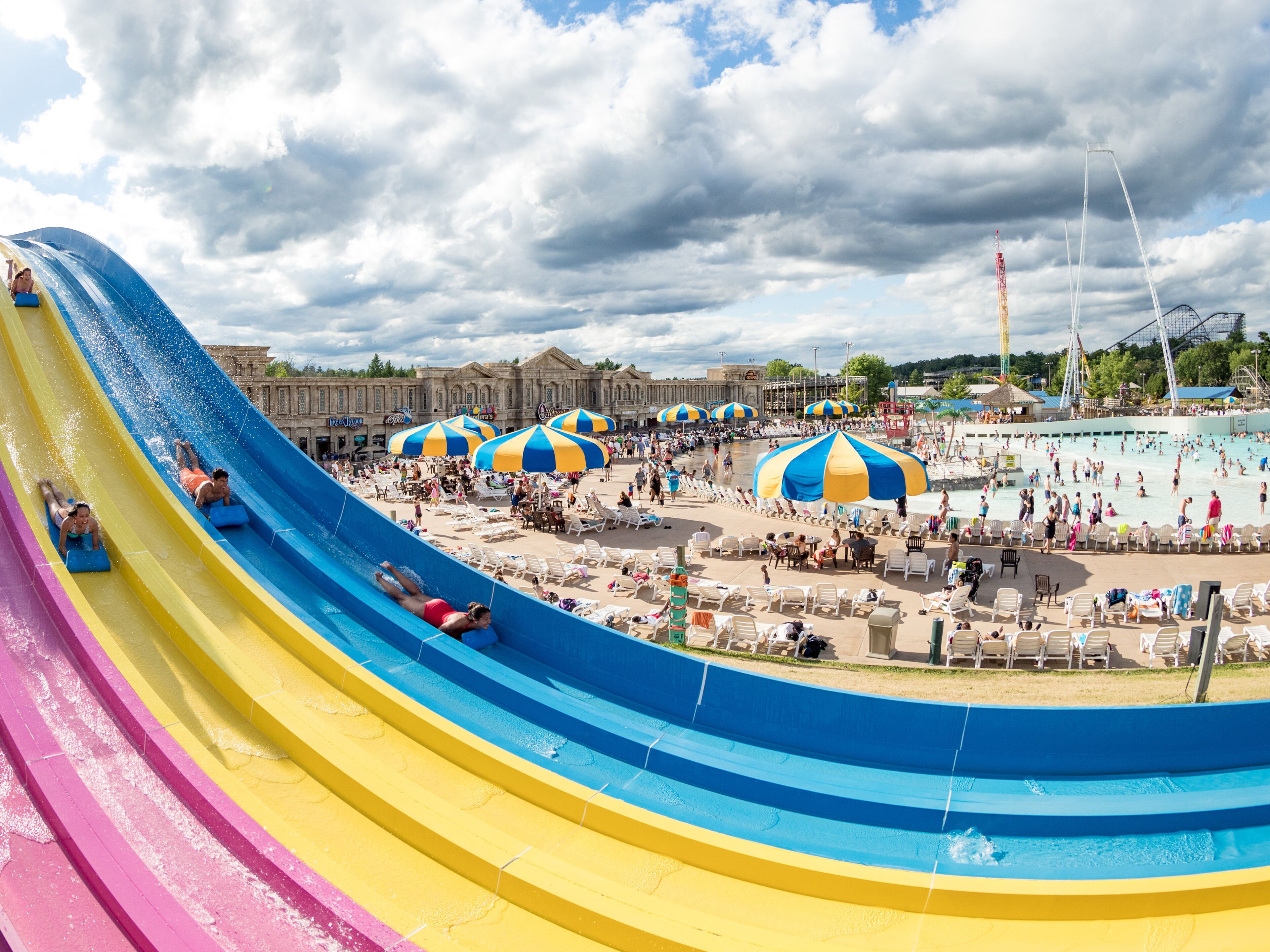 A water park with a large water slide, sun umbrellas, and a pool area.