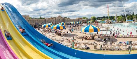 A water park with a large water slide, sun umbrellas, and a pool area.