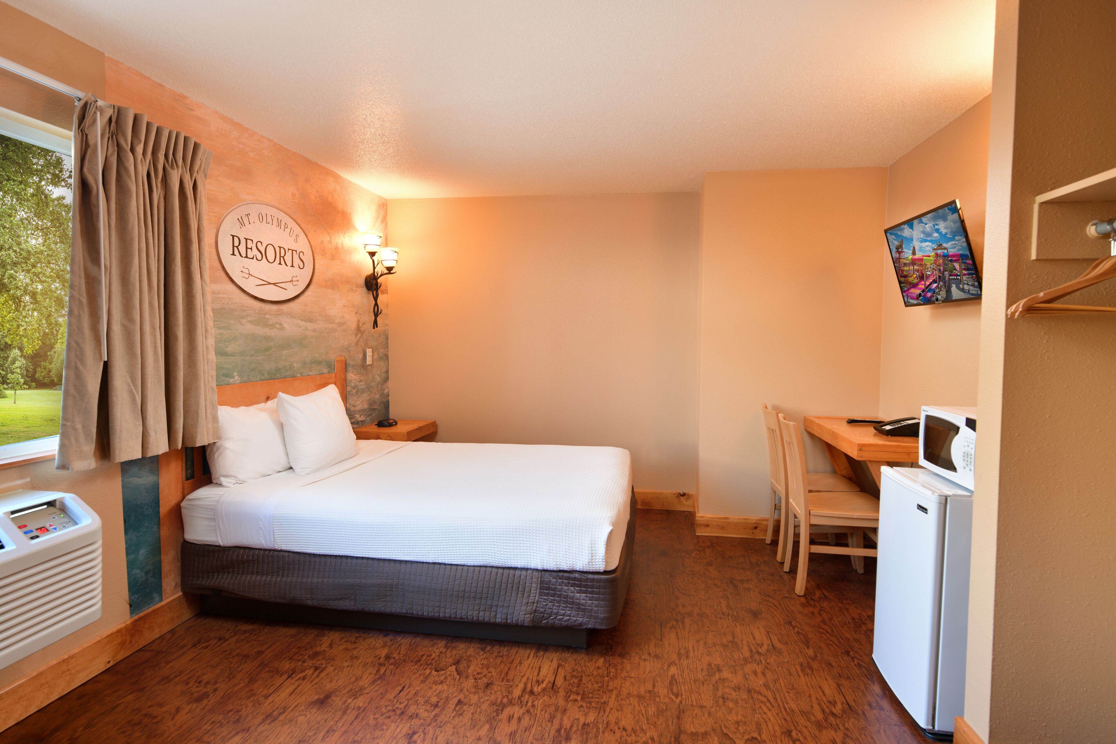 A bedroom with a bed, a desk, a chair, a microwave, and a wall-mounted sign.