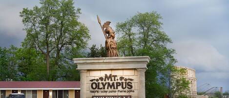 Señal de Monte Olimpo con una estatua de una figura sosteniendo una lanza, y referencias a los edificios 3-5.