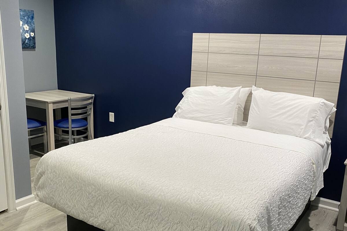 A bedroom with a bed, a nightstand, and a small table with chairs.