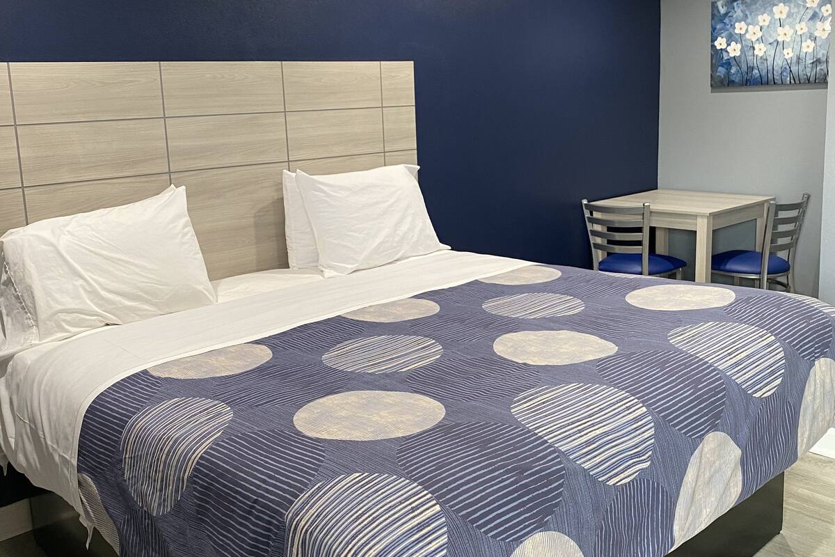 A hotel room with a bed, a small table, and chairs.