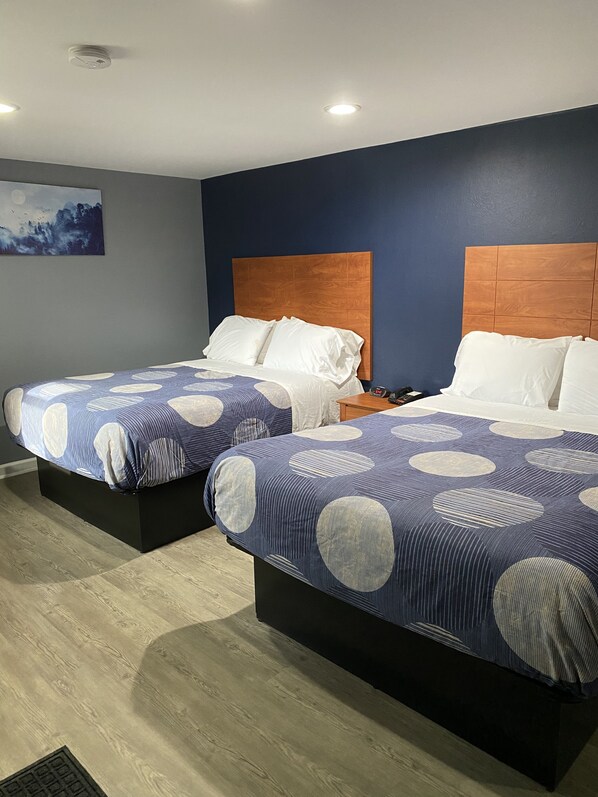 Two beds with matching headboards and bedding, a painting on the wall, and a wooden floor. - Dunmore Inn (Scranton)
