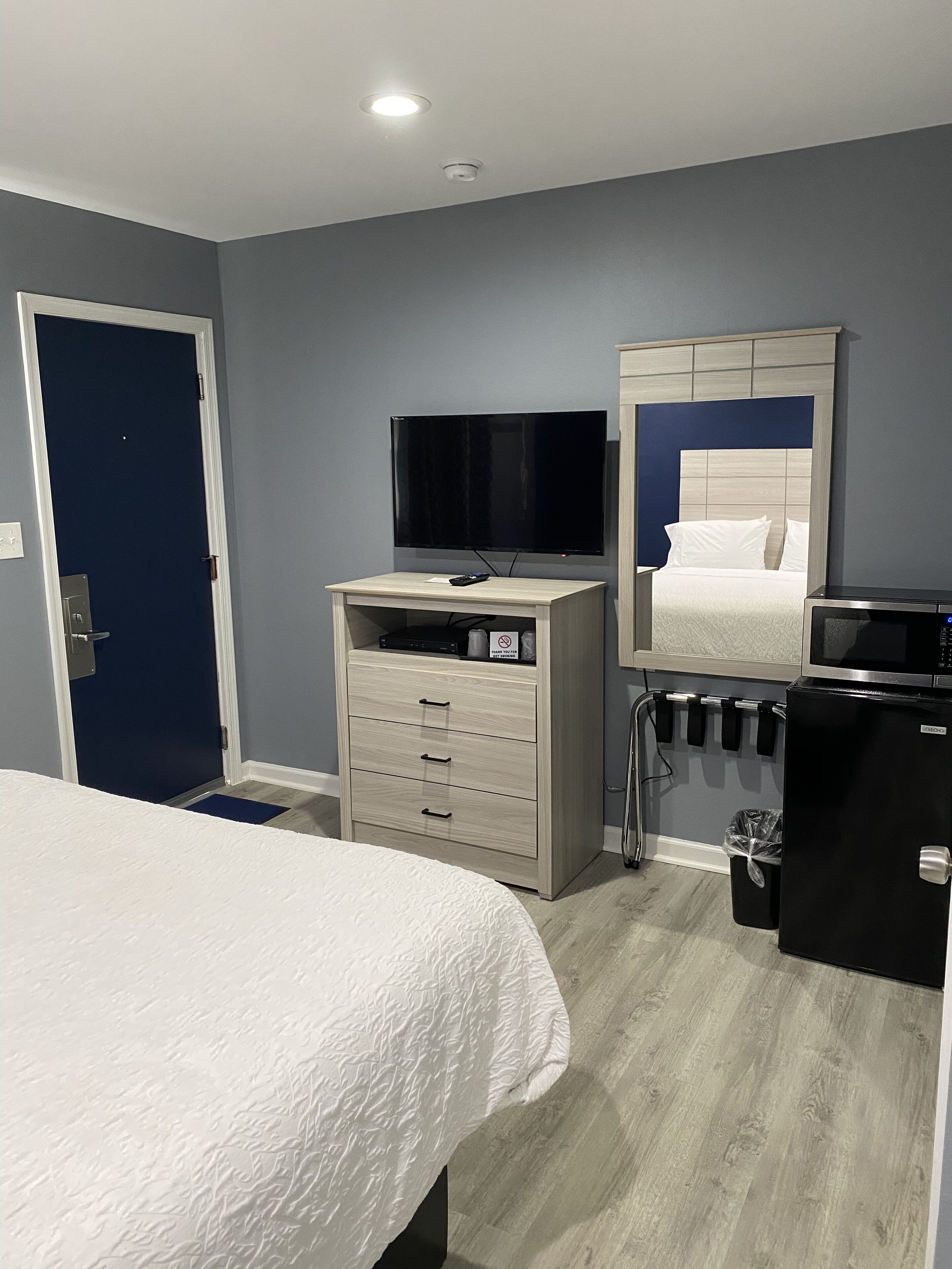 Una habitación de hotel con cama, televisión, minibar y espejo.