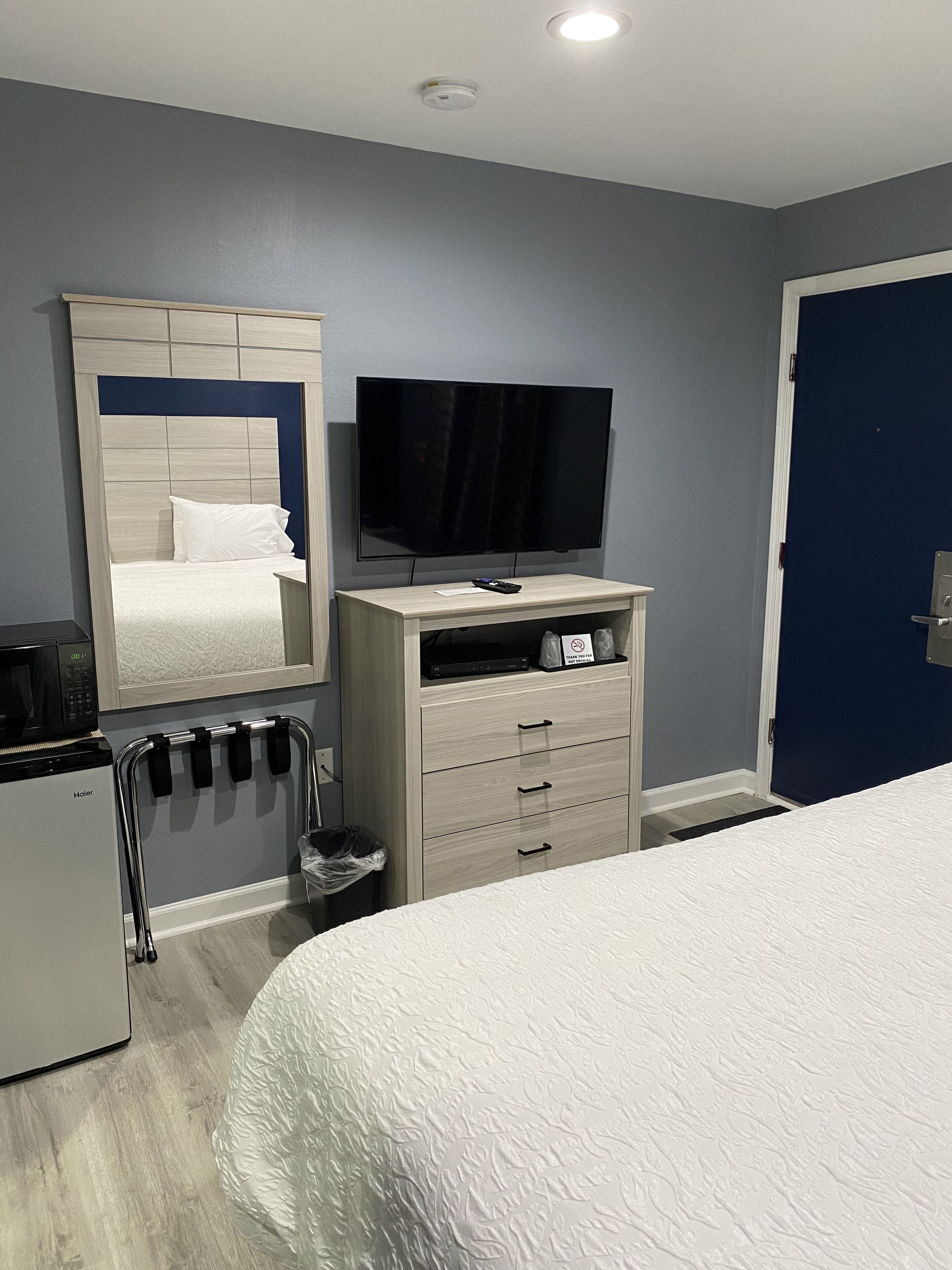 Una habitación de hotel con cama, televisión, minibar y puerta de baño.