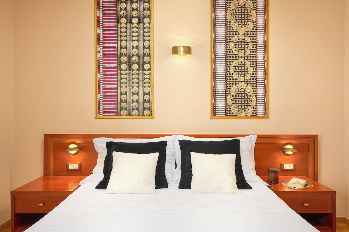A hotel room with a large bed, two bedside tables, and a wall-mounted light fixture.