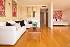 Una sala de estar moderna con un sofá blanco, una mesa de centro de madera y un jarrón decorativo.