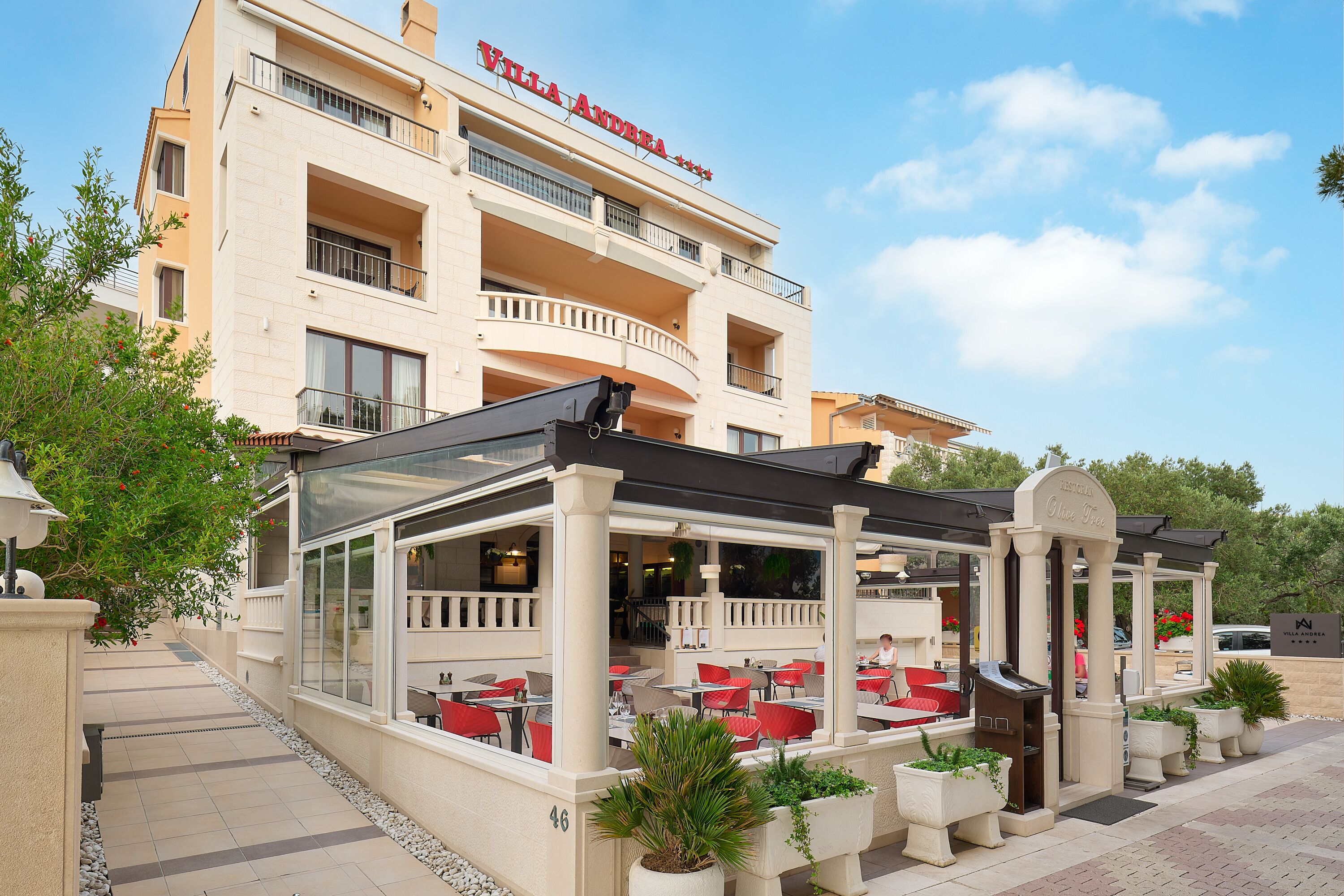 Un hotel con asientos al aire libre, un patio cubierto y un letrero que dice "Villa Andrea".