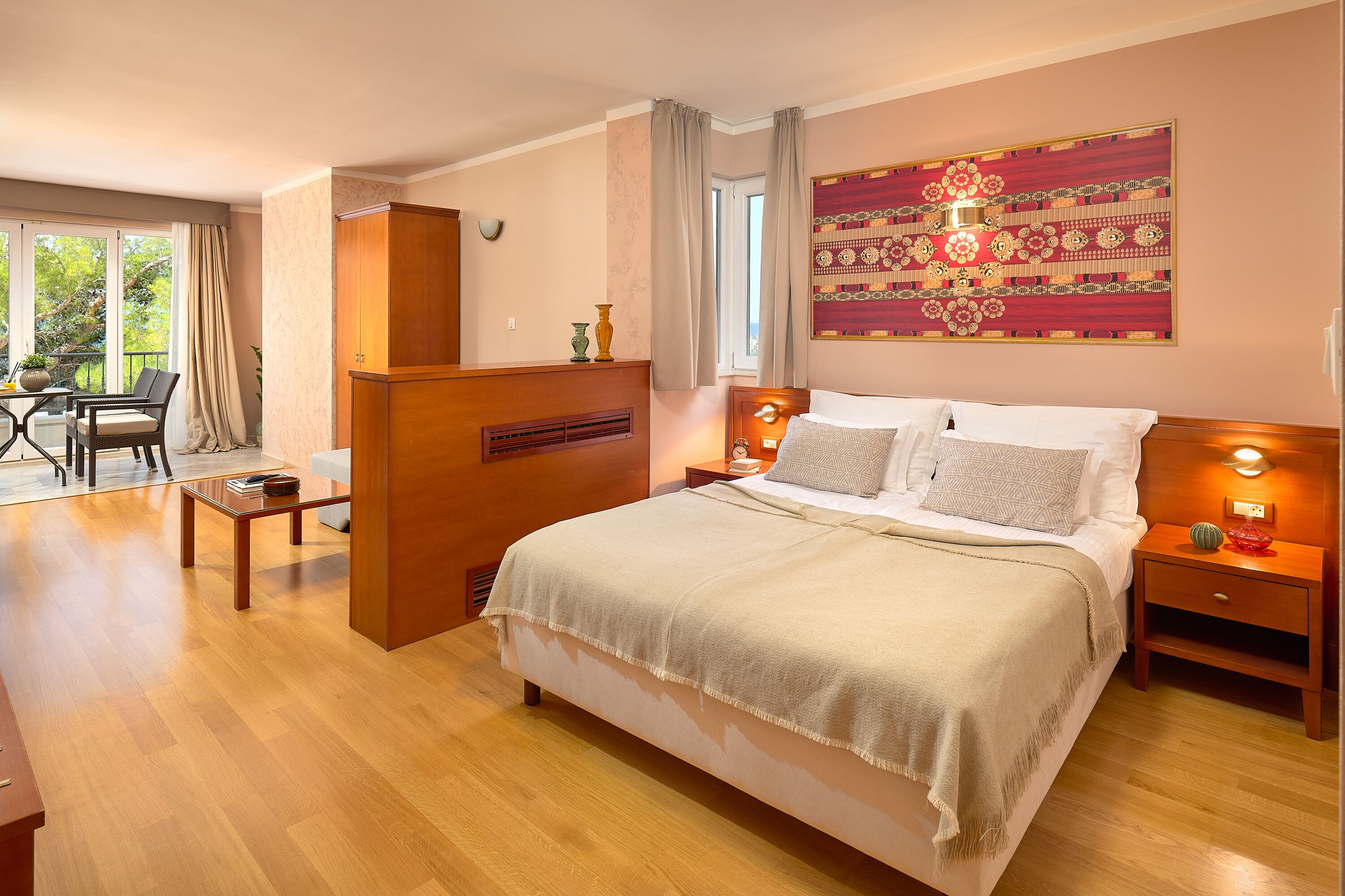 Un dormitorio bien iluminado con una cama grande, mesitas de noche, un armario de madera y una ventana con cortinas.