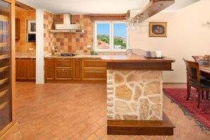 Una cocina con armarios de madera, una isla de piedra y vistas a través de una ventana.