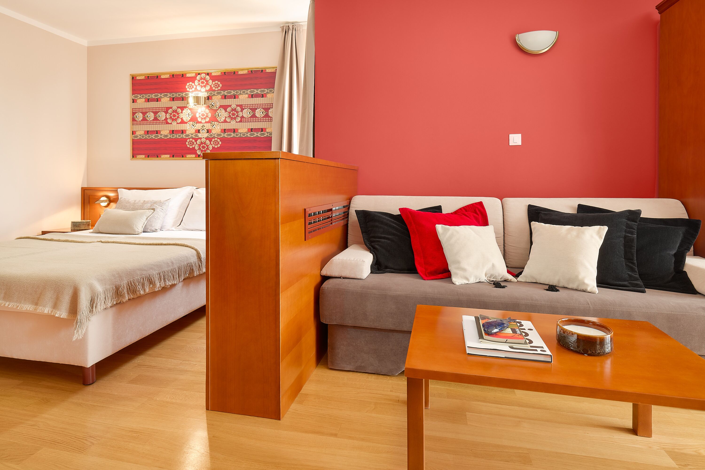 A hotel room with a bed, a sofa, a coffee table, and a wall with a decorative piece.