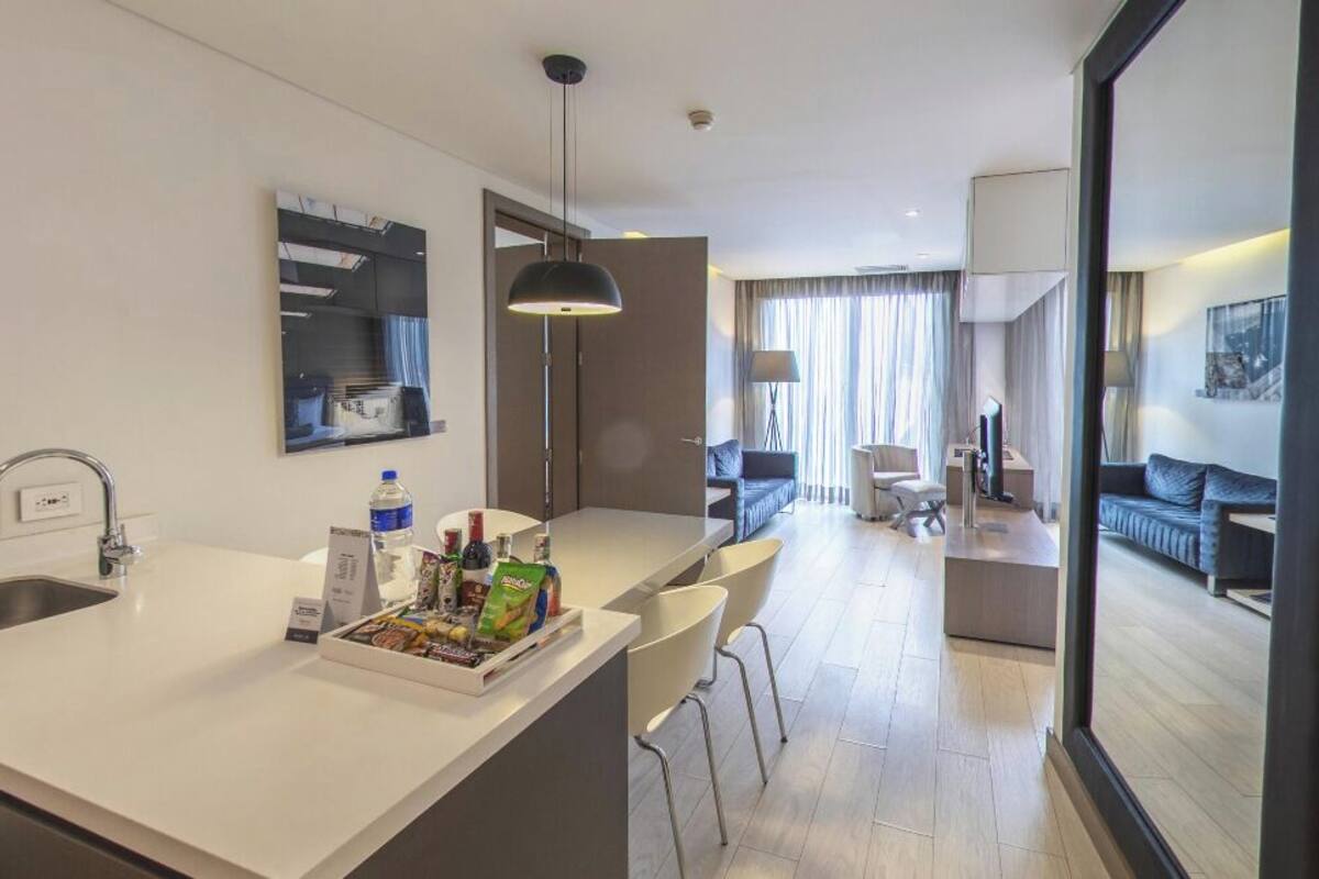 Una habitación de hotel moderna con cocina, comedor y sala de estar con sofá y sillones.