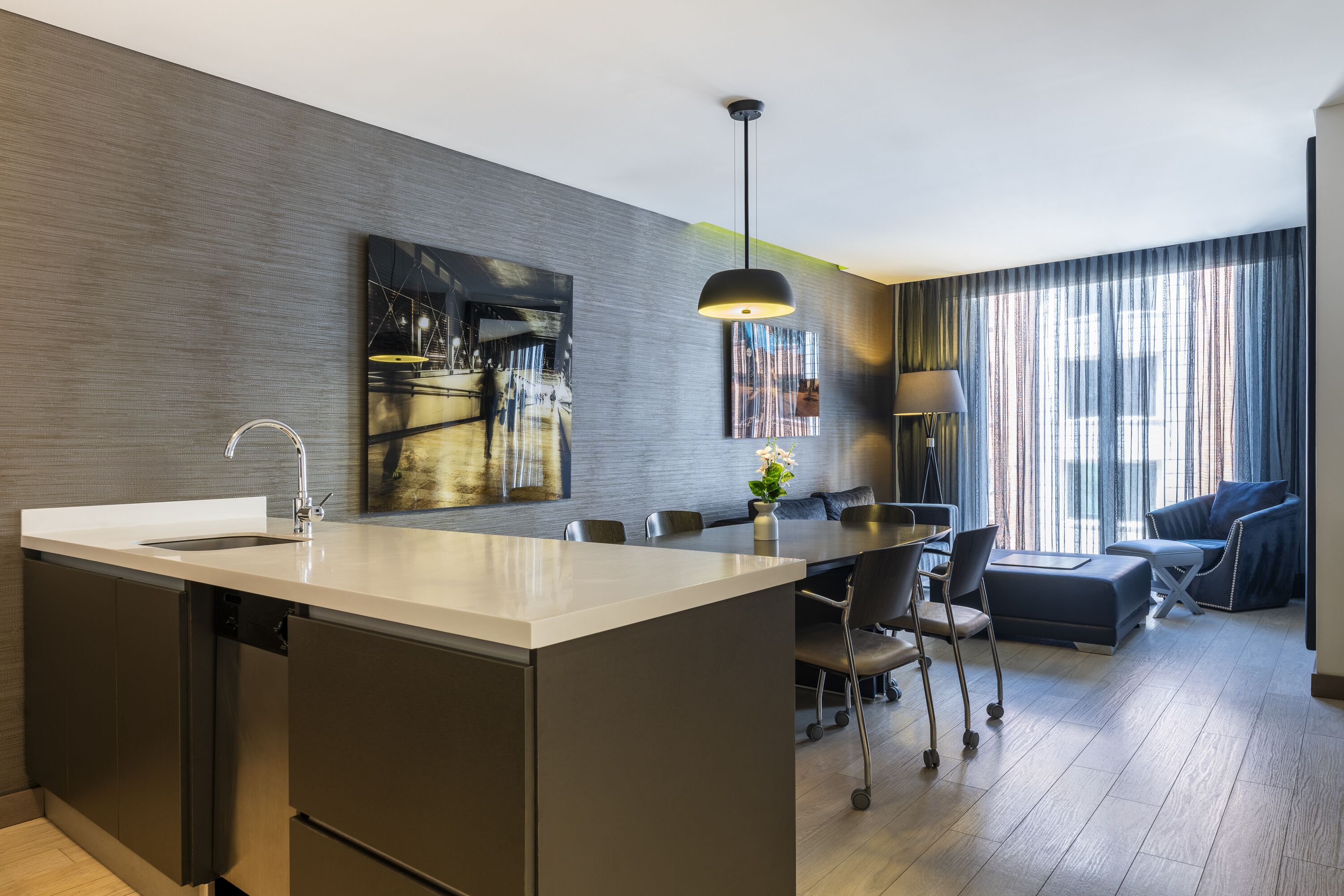 A modern kitchen with a central island, dining area with chairs, and a sofa.