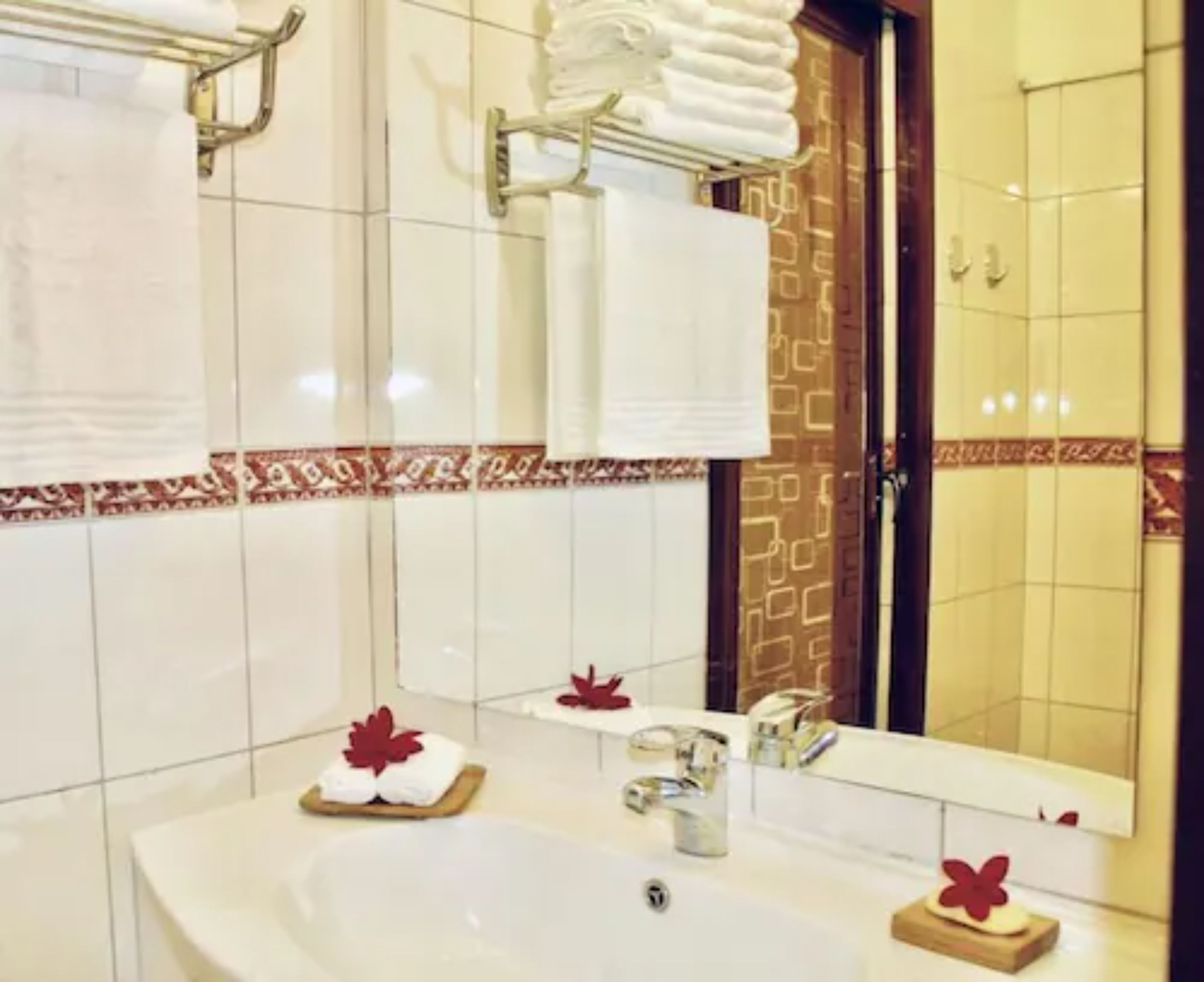 A bathroom with a large sink, a mirror, and a towel rack.
