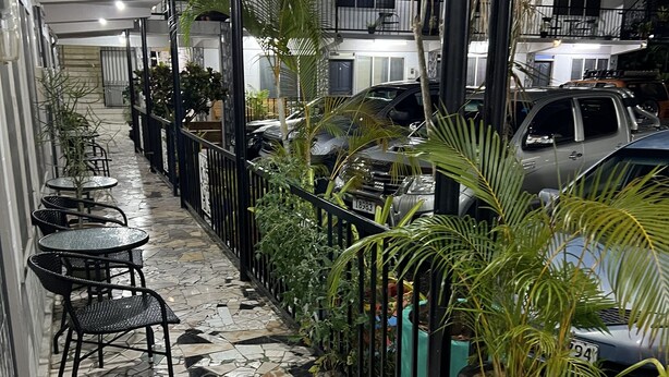 A tiled corridor with outdoor seating, potted plants, and parked cars. - Moatoga Hotel (Apia)