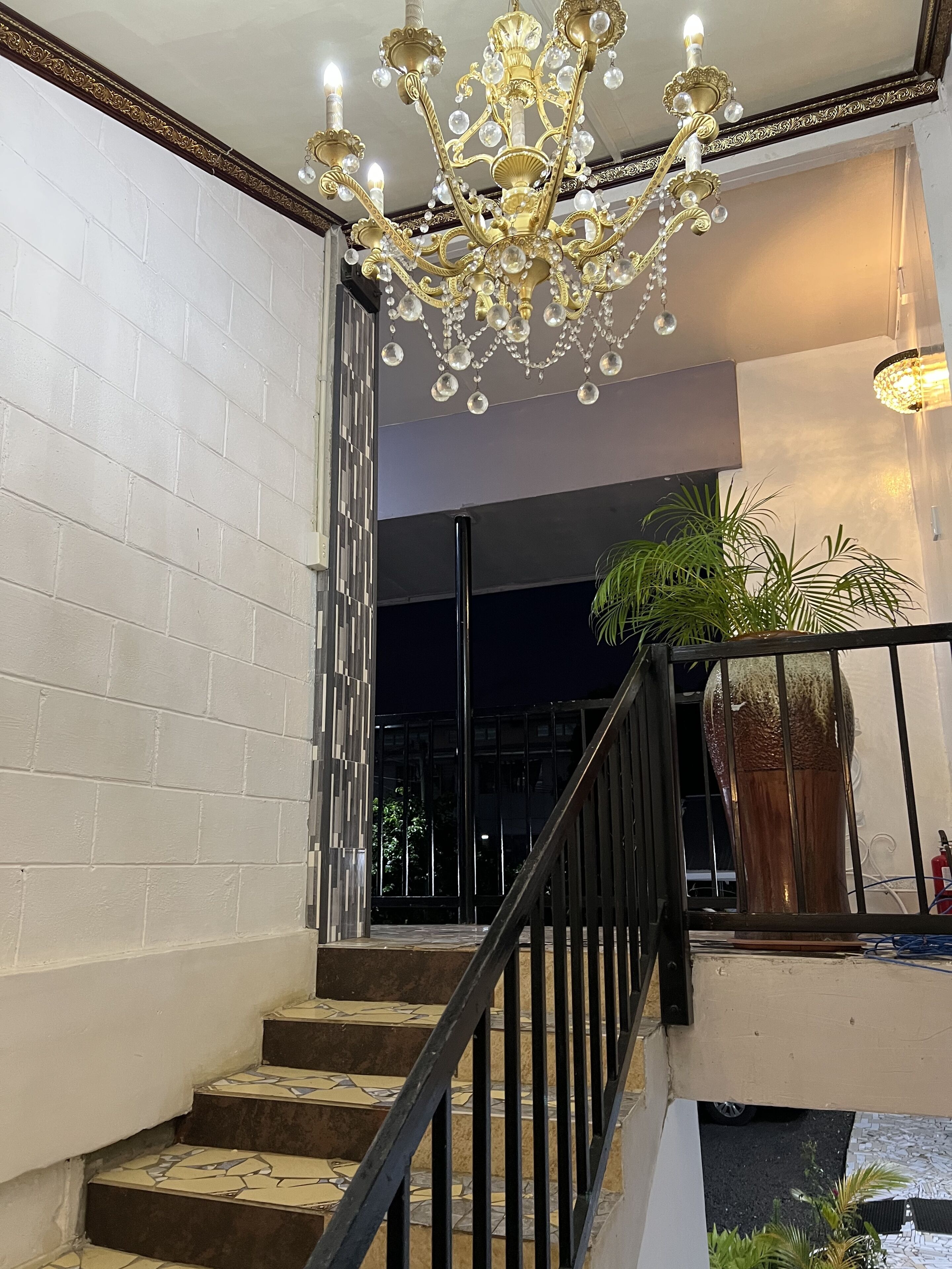 A staircase with a black railing, white brick walls, and a chandelier.
