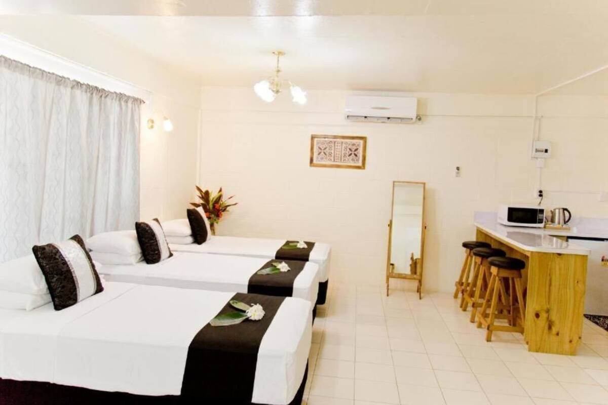 A hotel room with two beds, a small kitchenette, and a mirror.