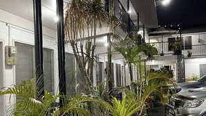 A modern building with a balcony, potted plants, and parked cars. - Moatoga Hotel (Apia)