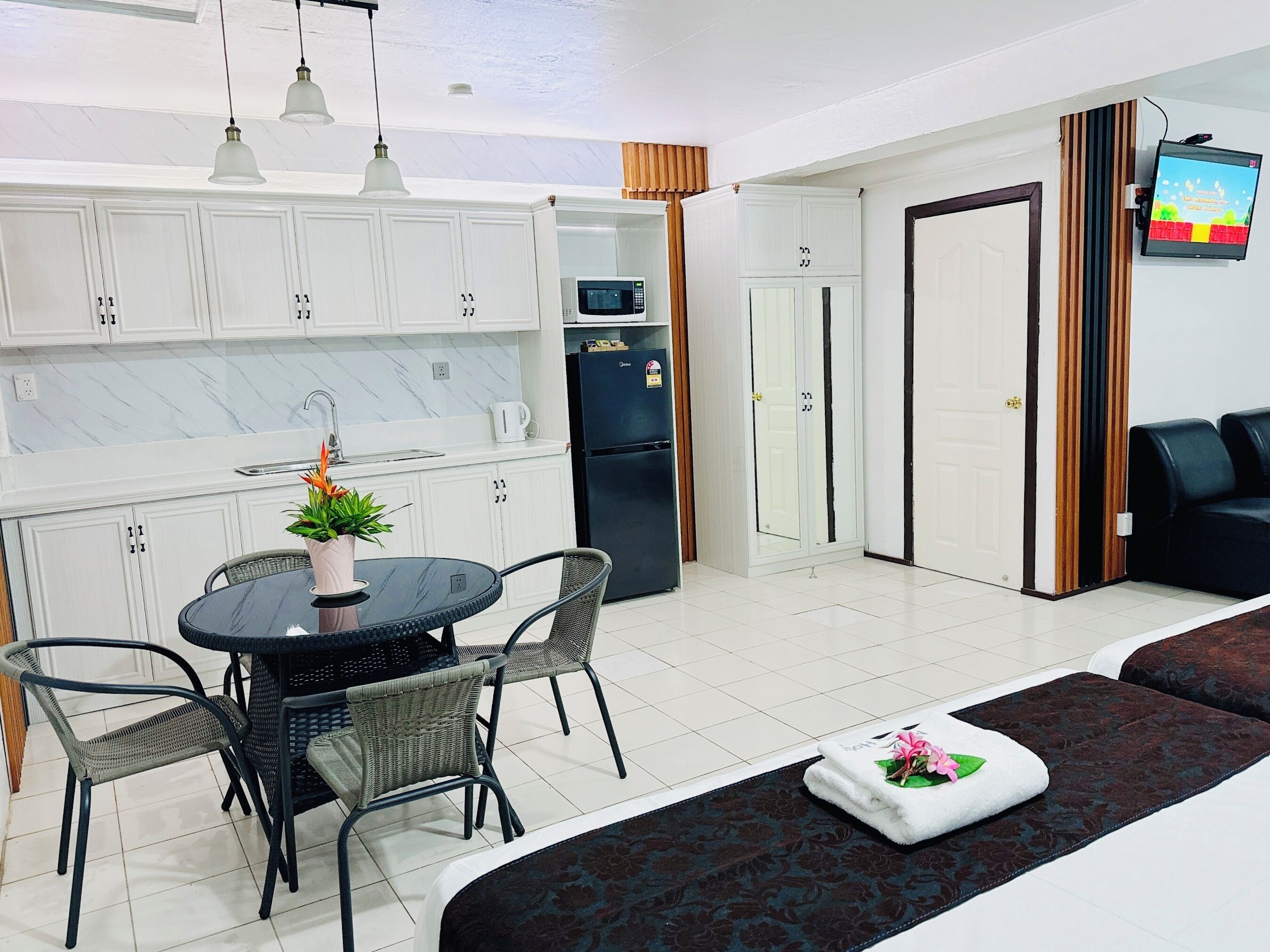 A modern kitchen with white cabinets, a dining table with chairs, a microwave, and a refrigerator.