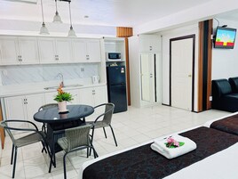 Une cuisine moderne avec des meubles blancs, une table à manger avec des chaises, un four à micro-ondes et un réfrigérateur.