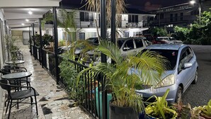 A covered outdoor seating area with tables and chairs, surrounded by potted plants and a parked car. - Moatoga Hotel (Apia)