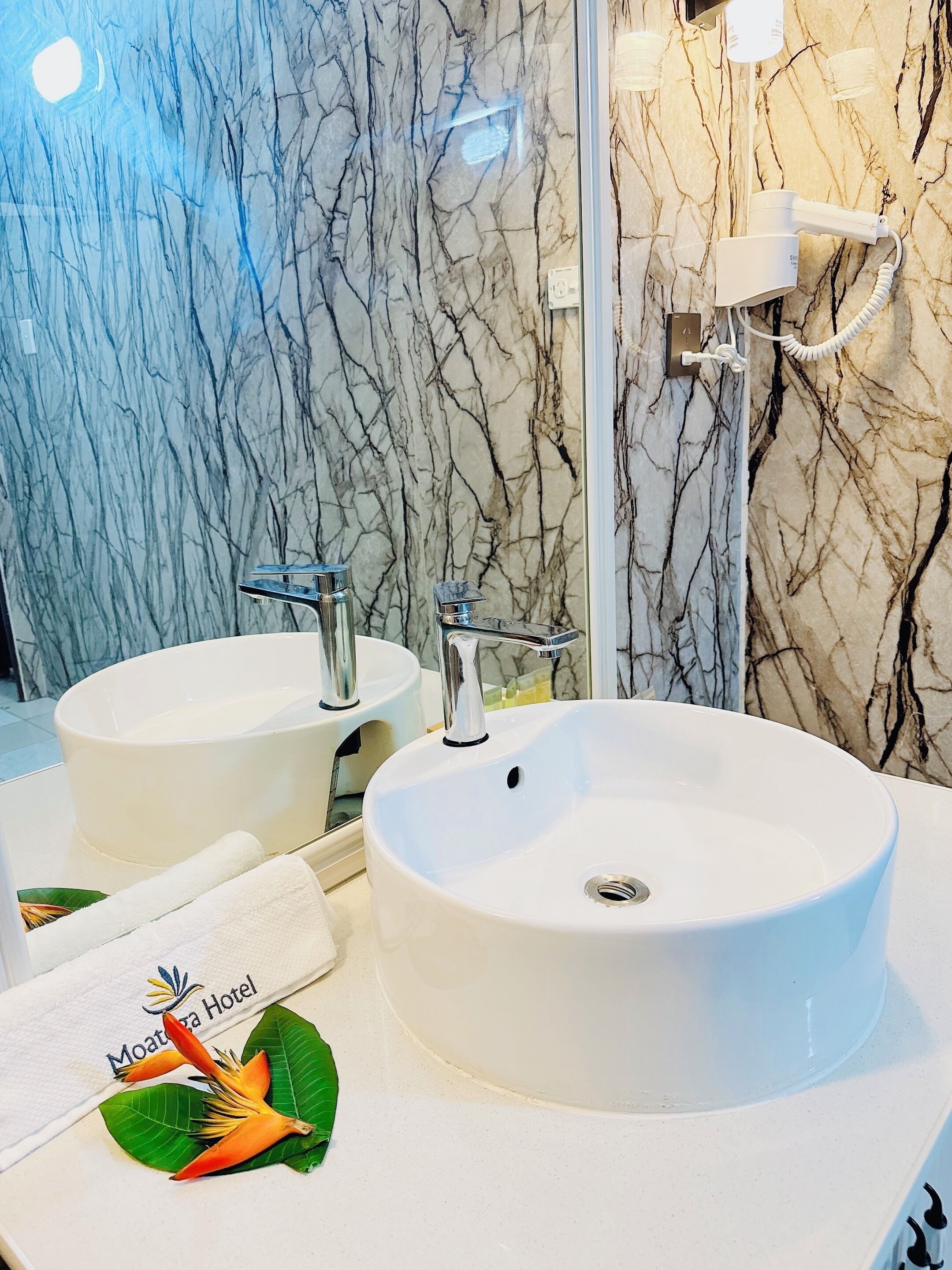 A bathroom with two sinks, a mirror, and a towel with a logo.