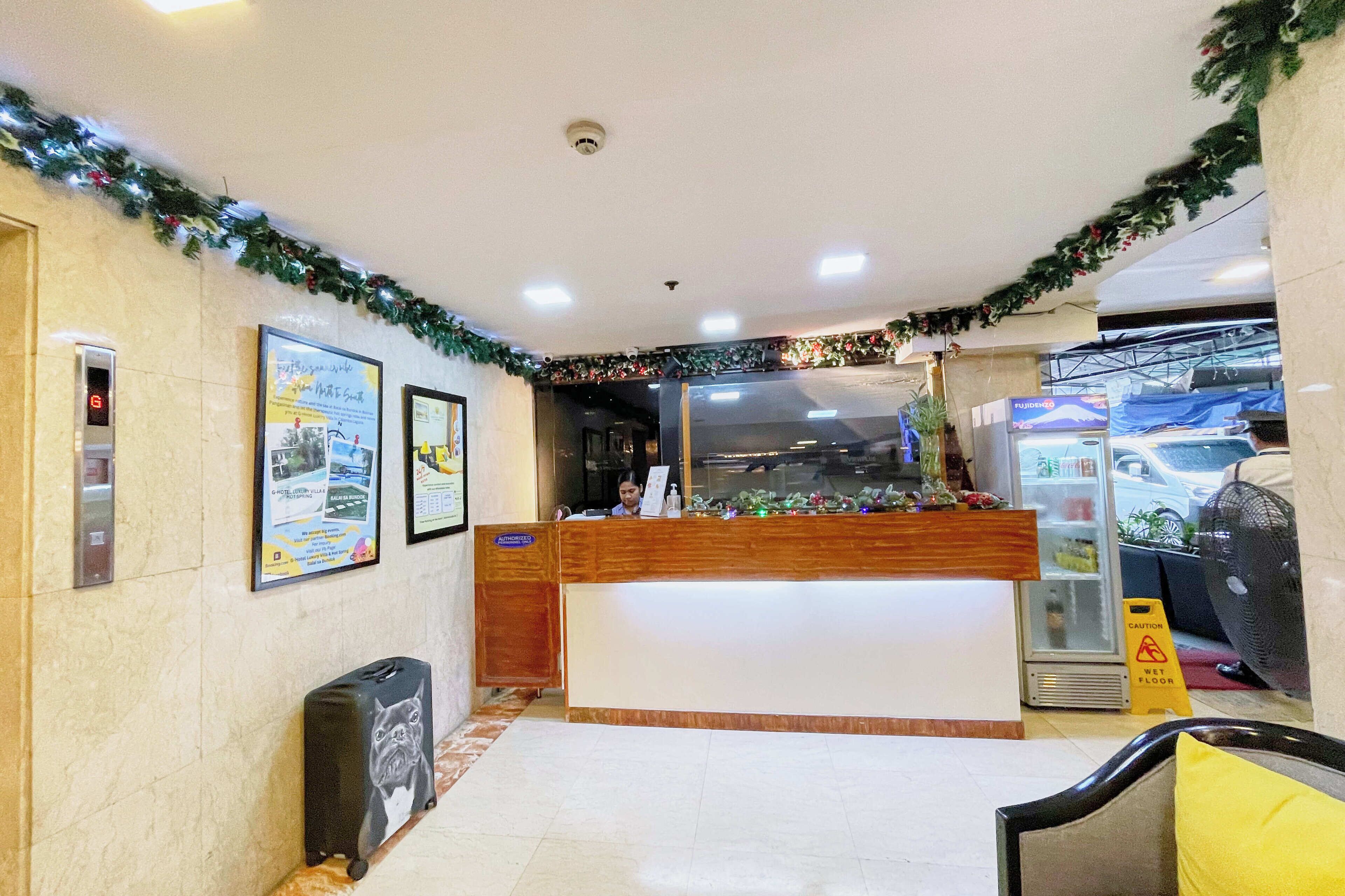 A reception area with a wooden desk, a digital display, and a glass door leading to a parking area.