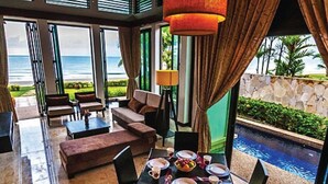A dining area with a view of the ocean, a pool, and a stone wall. - Borneo Beach Villa & Suite (Kota Kinabalu)