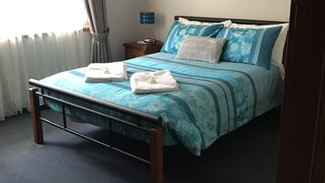 Quarto bem arrumado com cama, mesa de cabeceira, luminária e um quadro na parede.