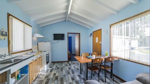 A compact kitchen with a wooden countertop, a sink, and a television mounted on the wall. - Havana Villas (Emu Point)
