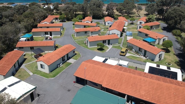 A coastal resort with multiple bungalow-style buildings, each with a red-tiled roof, arranged around a central paved area. - Havana Villas (Emu Point)