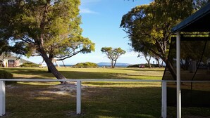 A grassy area with trees and a view of the sea. - Havana Villas (Emu Point)
