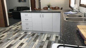 A kitchen with white cabinets, a granite countertop, and a wooden floor. - Havana Villas (Emu Point)