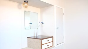 A room with a white wall, a wooden vanity with two drawers, a mirror, and a door. - Gateway International Motel (Rotorua)
