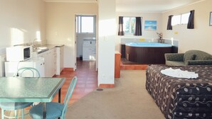 A room with a bed, a table with chairs, a kitchenette, a bathroom, and a window with curtains. - Gateway International Motel (Rotorua)