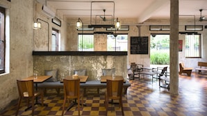 Un restaurant amb sostre alt i biges de fusta, terres de pissos quadriculats i taules i cadires de fusta.