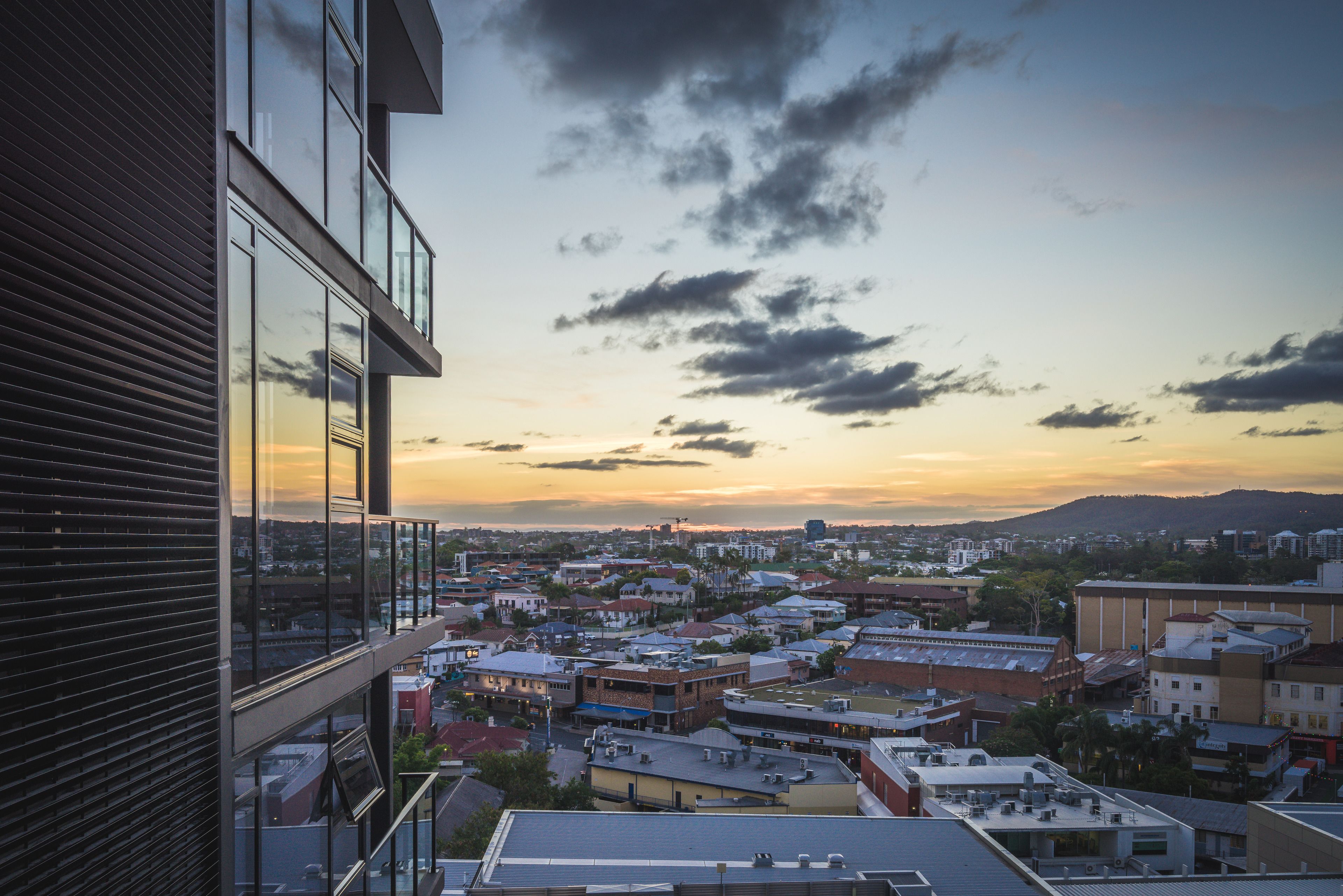 A cityscape with a modern building featuring large windows and a balcony.